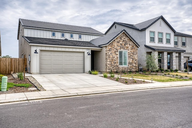 modern farmhouse style home with concrete driveway, fence, stone siding, and stucco siding