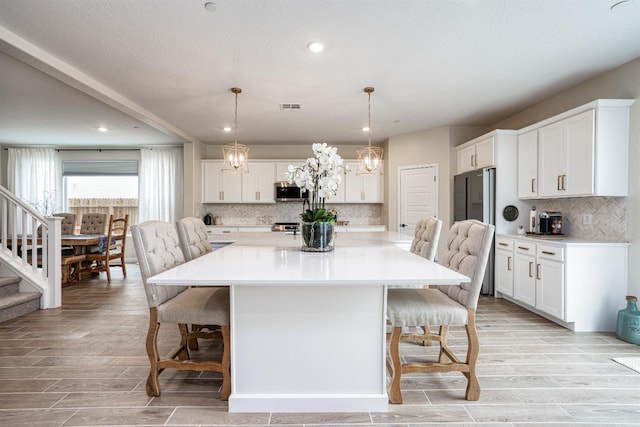 kitchen featuring visible vents, a breakfast bar area, wood tiled floor, and white cabinetry