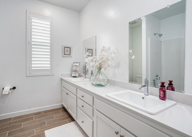 bathroom featuring walk in shower, toilet, wood finish floors, and a sink