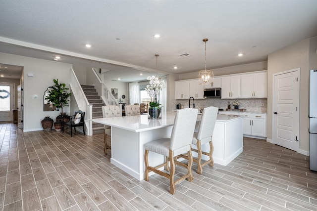 kitchen with tasteful backsplash, appliances with stainless steel finishes, a breakfast bar area, light countertops, and wood tiled floor