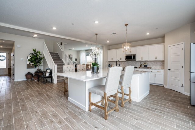 1093 Traverse Dr S, Madera, CA 93636 - kitchen with light countertops, stainless steel microwave, a breakfast bar, recessed lighting, and light wood-style flooring