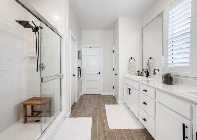 1093 Traverse Dr S, Madera, CA 93636 - bathroom featuring double vanity, a stall shower, wood finish floors, a sink, and baseboards