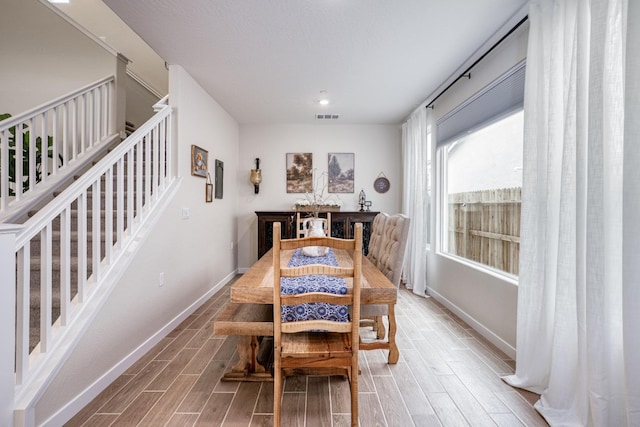 dining area featuring stairs, visible vents, baseboards, and wood tiled floor