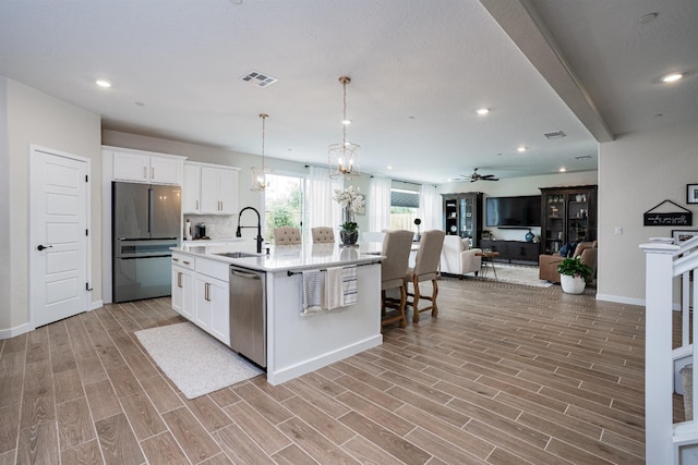 kitchen featuring visible vents, wood finish floors, freestanding refrigerator, a sink, and stainless steel dishwasher