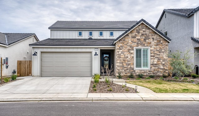 view of front of house with stone siding, fence, roof with shingles, concrete driveway, and an attached garage