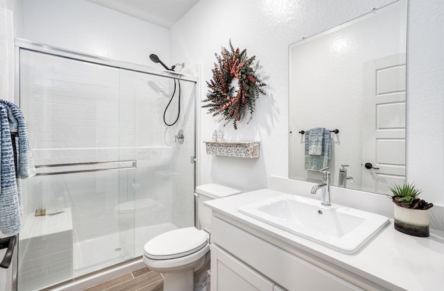 full bathroom featuring vanity, toilet, wood finished floors, and a shower stall