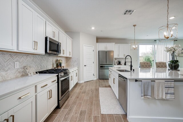 1093 Traverse Dr S, Madera, CA 93636 - kitchen with a notable chandelier, a sink, light wood finished floors, stainless steel appliances, and visible vents
