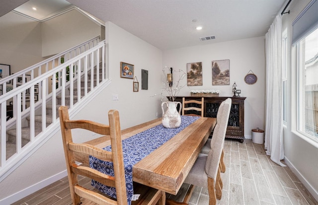 dining room featuring stairway, baseboards, visible vents, and wood tiled floor