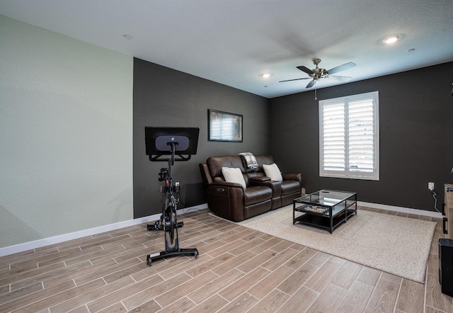 living room featuring a ceiling fan, baseboards, and wood tiled floor