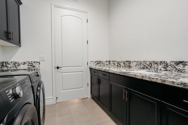 clothes washing area featuring washer and clothes dryer, cabinet space, light tile patterned flooring, and a sink