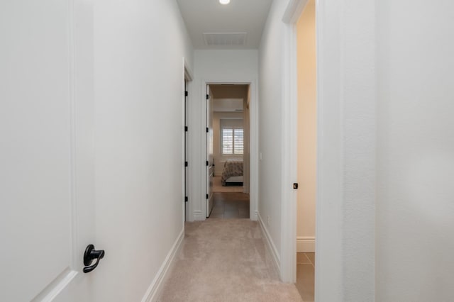hall featuring visible vents, light colored carpet, and baseboards