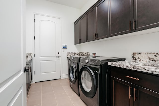 laundry area featuring separate washer and dryer, light tile patterned floors, and cabinet space