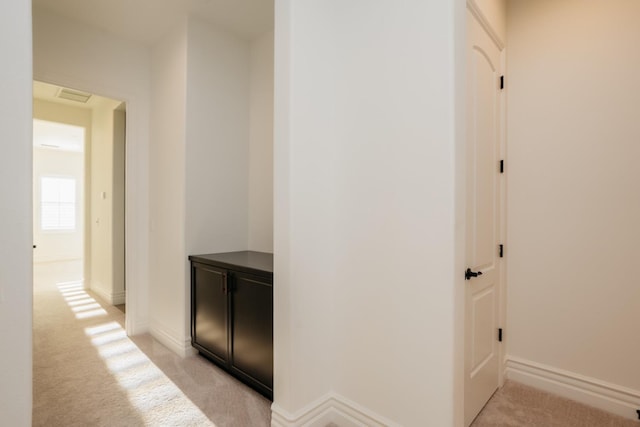 hallway featuring baseboards, light carpet, and visible vents