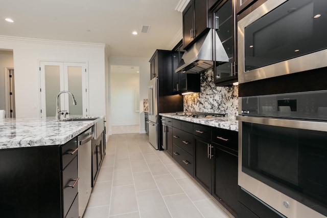 kitchen with tasteful backsplash, under cabinet range hood, appliances with stainless steel finishes, dark cabinetry, and a sink
