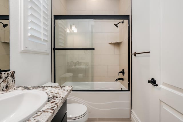 bathroom with vanity, toilet, and combined bath / shower with glass door