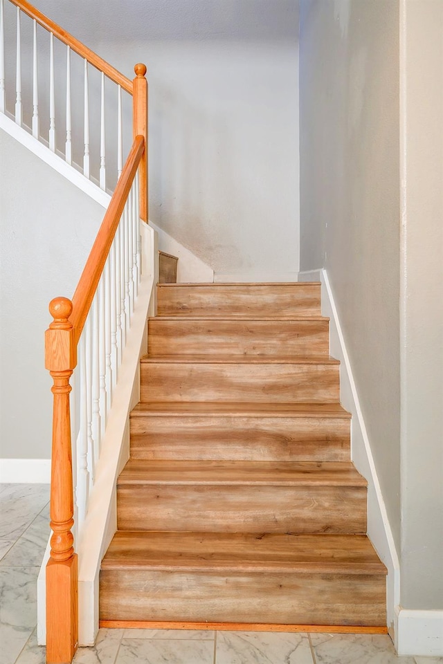 stairway with baseboards and marble finish floor