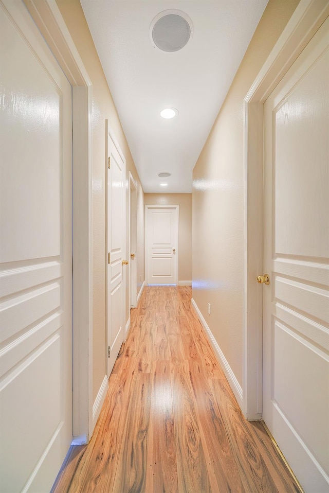 corridor featuring baseboards and light wood finished floors