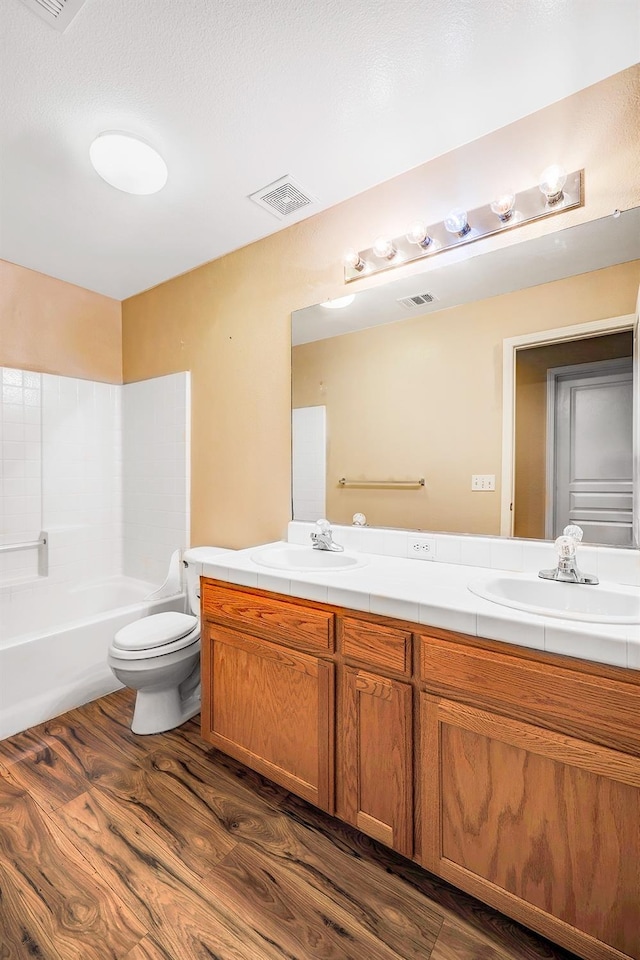 bathroom with toilet, wood finished floors, visible vents, and a sink