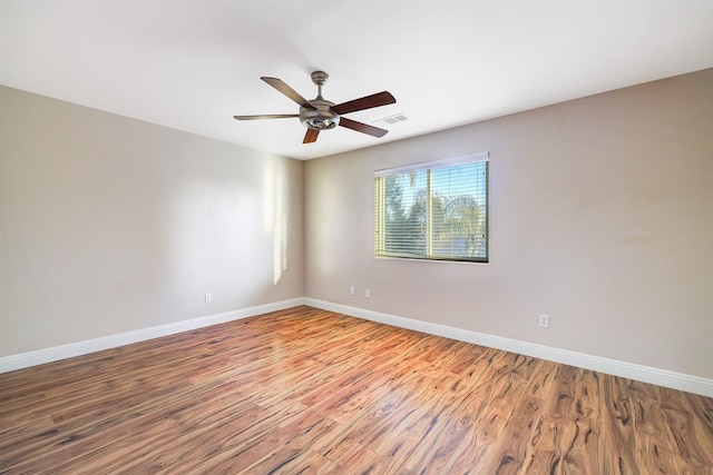 empty room with visible vents, baseboards, ceiling fan, and wood finished floors