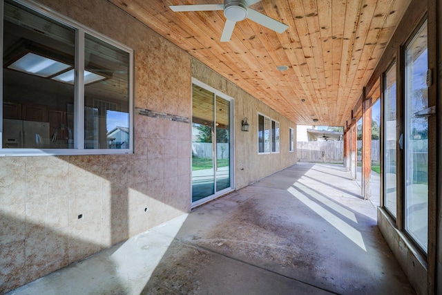 unfurnished sunroom featuring wood ceiling and ceiling fan