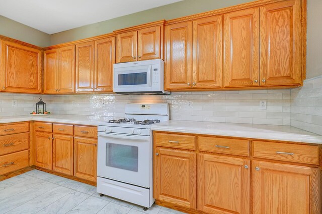 kitchen with brown cabinetry, white appliances, and light countertops