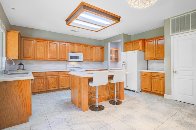 kitchen with white appliances, visible vents, a sink, marble finish floor, and a center island