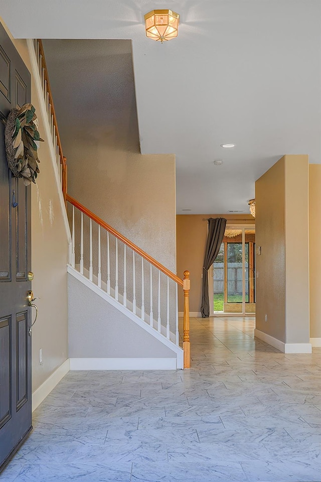 foyer entrance with stairway, marble finish floor, and baseboards