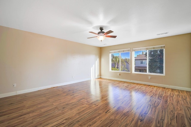 unfurnished room with visible vents, wood finished floors, baseboards, and ceiling fan