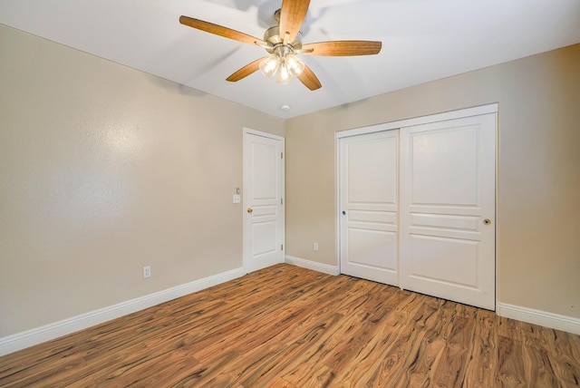 unfurnished bedroom with a ceiling fan, wood finished floors, baseboards, and a closet