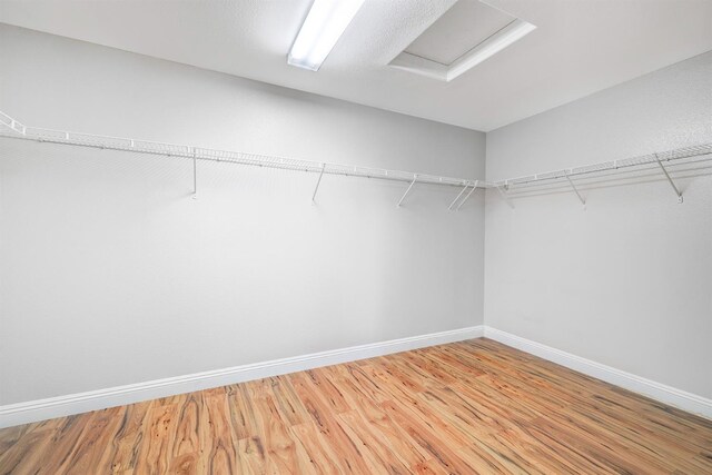 spacious closet featuring light wood finished floors and attic access