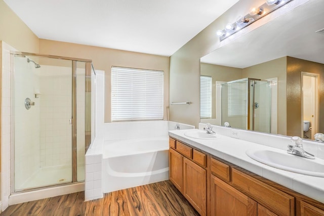 full bathroom featuring a shower stall, a bath, wood finished floors, and a sink