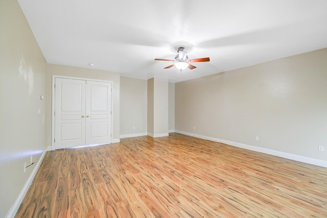 empty room featuring a ceiling fan, baseboards, and light wood finished floors