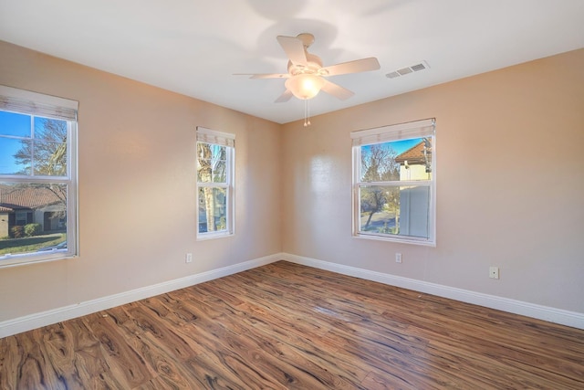 empty room featuring visible vents, baseboards, wood finished floors, and a ceiling fan