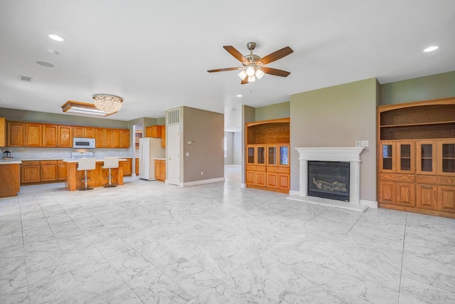 unfurnished living room featuring a glass covered fireplace, marble finish floor, visible vents, and a ceiling fan