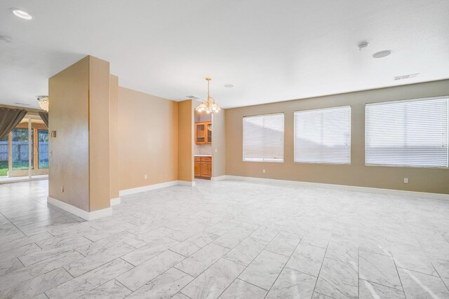 unfurnished room with a chandelier, visible vents, marble finish floor, and baseboards