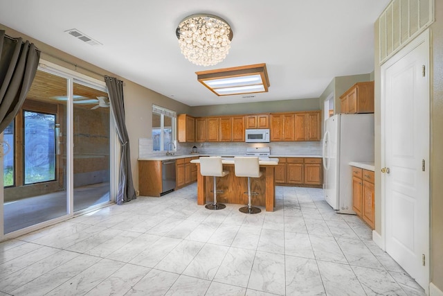 kitchen with white appliances, brown cabinetry, visible vents, light countertops, and marble finish floor