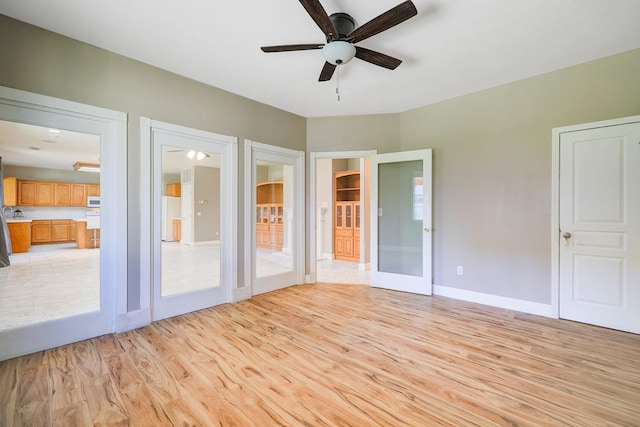 interior space featuring light wood finished floors, ceiling fan, baseboards, french doors, and freestanding refrigerator