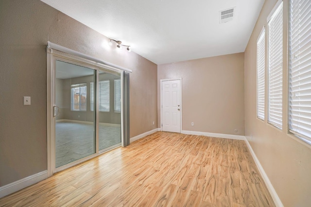 unfurnished room with visible vents, light wood-type flooring, and baseboards