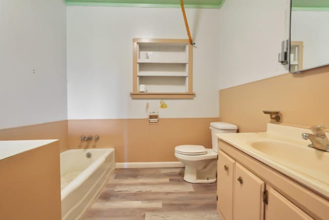 bathroom with a bath, toilet, vanity, and wood finished floors