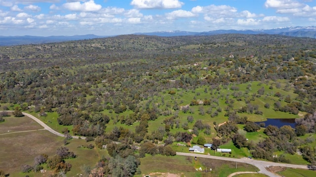 aerial view featuring a wooded view and a water and mountain view