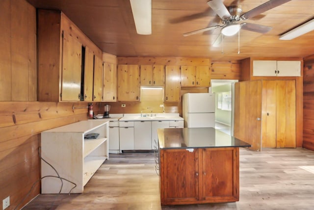 kitchen with light wood finished floors, wooden walls, and freestanding refrigerator