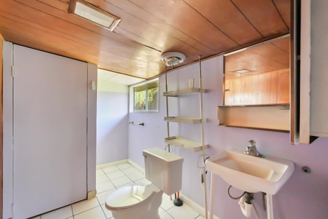 half bath featuring baseboards, a sink, tile patterned flooring, wood ceiling, and toilet