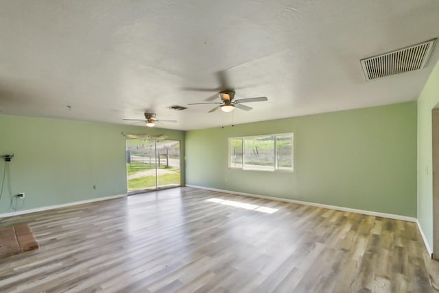 unfurnished room featuring wood finished floors, visible vents, and baseboards