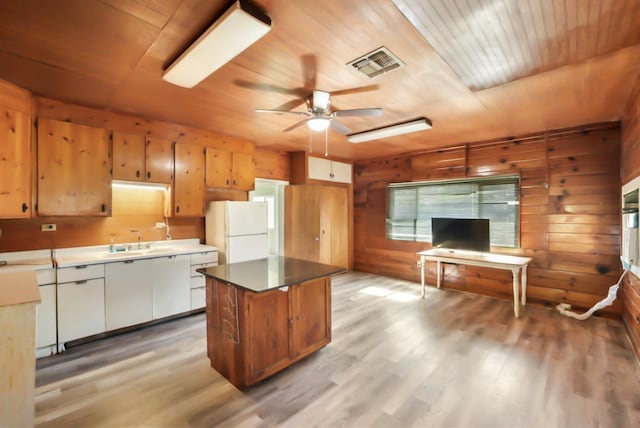 kitchen featuring visible vents, freestanding refrigerator, wooden walls, wooden ceiling, and light wood finished floors