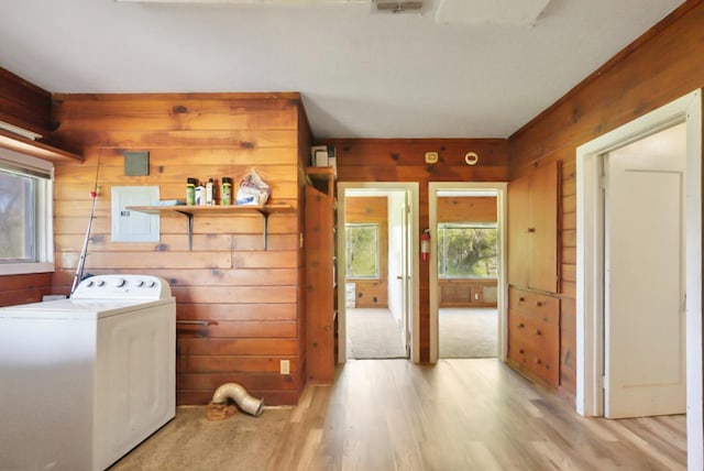 clothes washing area featuring light wood-style floors, wooden walls, washer / dryer, and laundry area