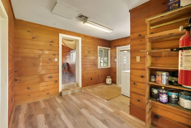 hallway featuring washer / dryer, visible vents, light wood-style flooring, and wood walls