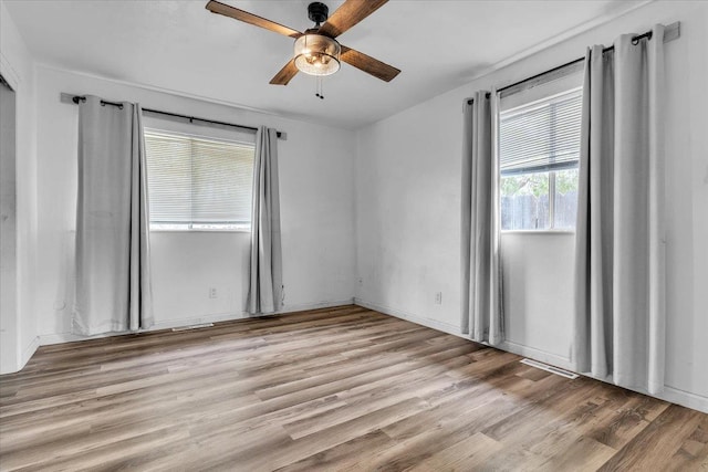 empty room featuring visible vents, a ceiling fan, and light wood-style floors