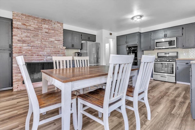 dining room featuring light wood-style floors and brick wall