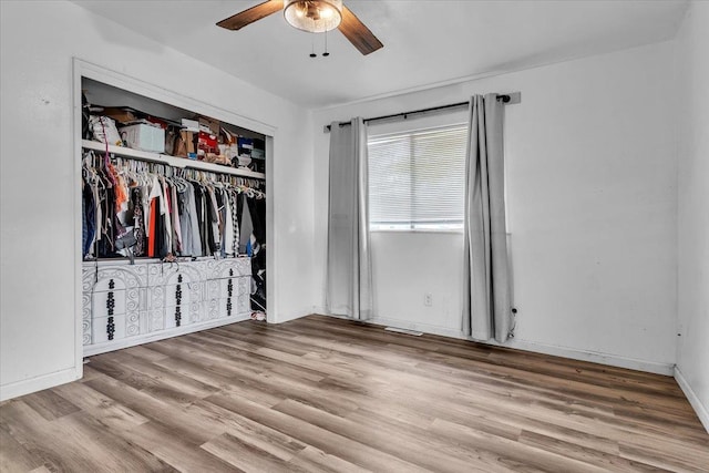 unfurnished bedroom featuring visible vents, wood finished floors, a closet, baseboards, and ceiling fan