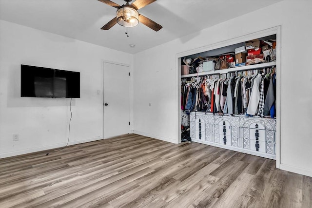 unfurnished bedroom with a closet, a ceiling fan, baseboards, and wood finished floors